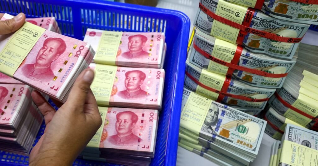 A bank employee count China’s renminbi (RMB) or yuan notes next to U.S. dollar notes at a Kasikornbank in Bangkok