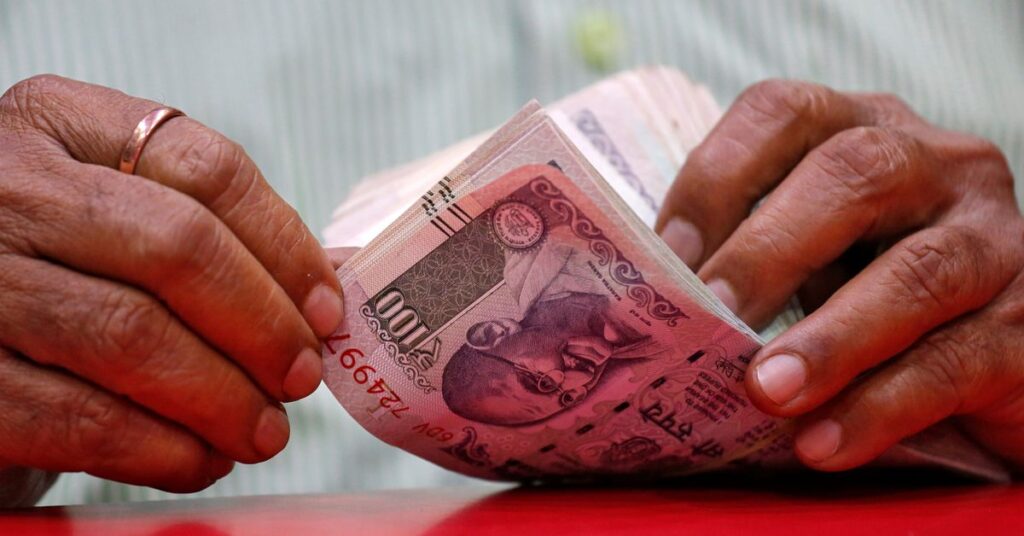 الروبية الهندية ترتفع بعد أن أكدت البيانات من جديد أن بنك الاحتياطي الفيدرالي قد رفع أسعار الفائدة A man counts Indian currency notes inside a shop in Mumbai