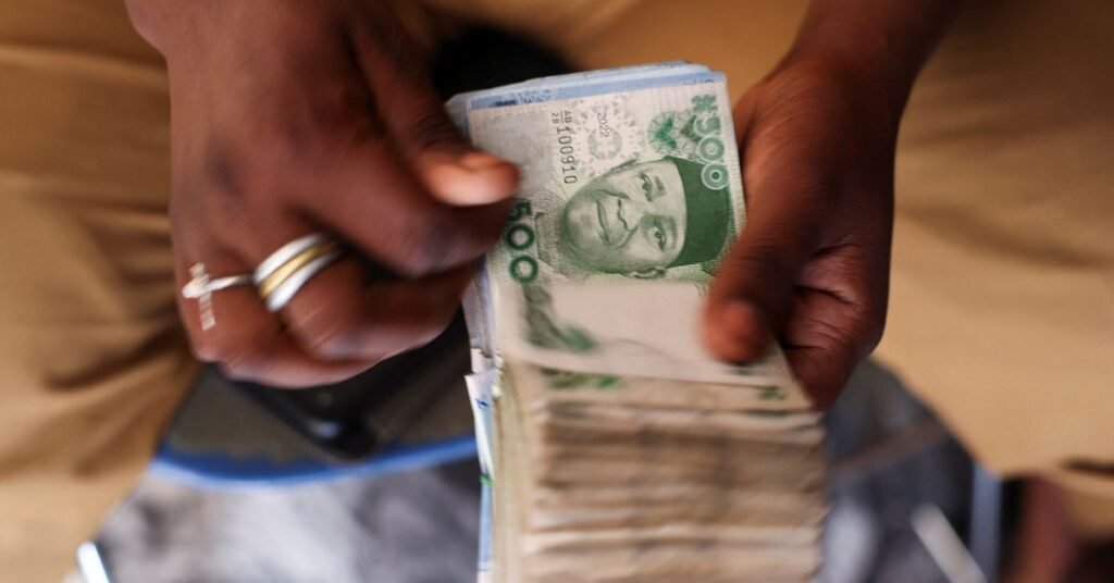 Man counts Nigerian naira notes in a market place ahead of Nigeria