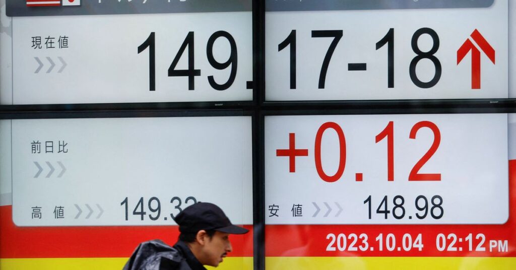 A man walks past an electric monitor displaying the Japanese yen exchange rate against the U.S. dollar outside a brokerage in Tokyo