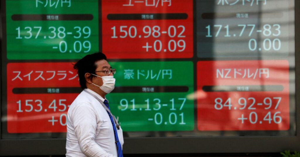 A man walks past an electric monitor displaying the Japanese yen exchange rate against the U.S. dollar, Euro and other foreign currencies outside a brokerage in Tokyo