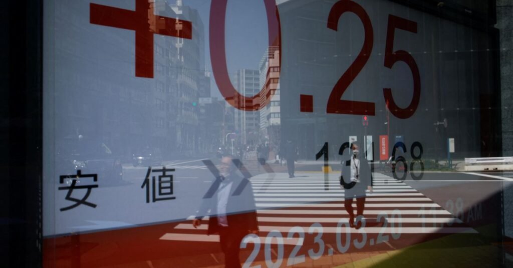 A reflection of passersby walking is seen on an electronic board showing Japan