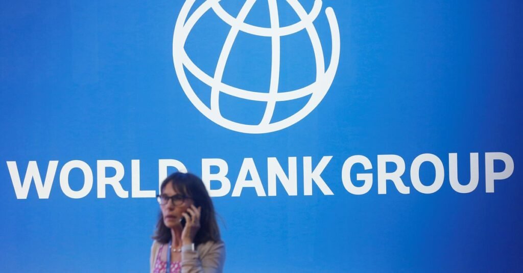 A participant stands near a logo of World Bank at the International Monetary Fund - World Bank Annual Meeting 2018 in Nusa Dua