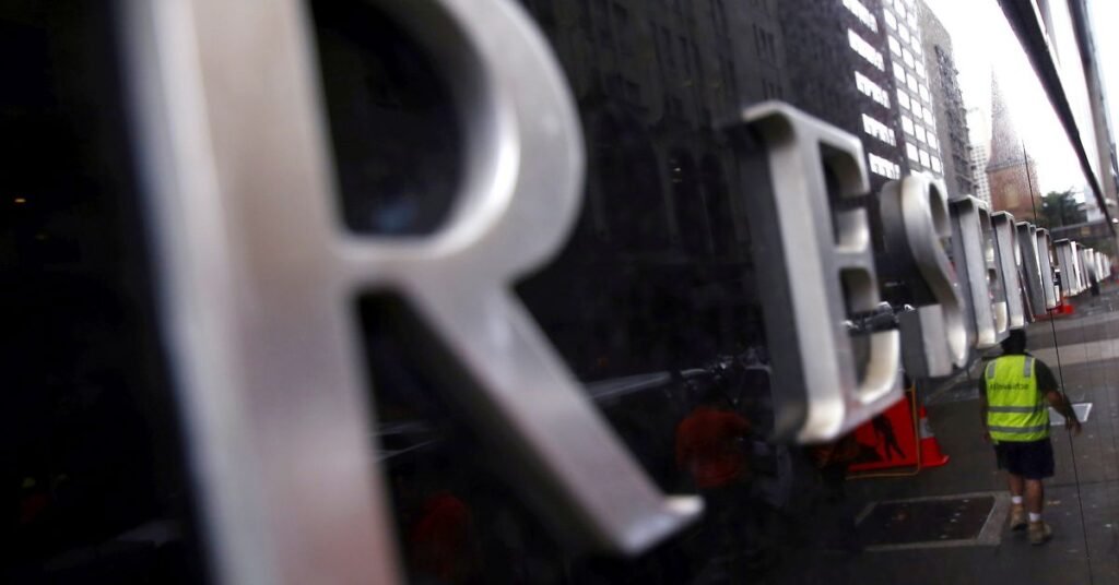 A worker is reflected in a wall of the Reserve Bank of Australia head office in central Sydney, Australia