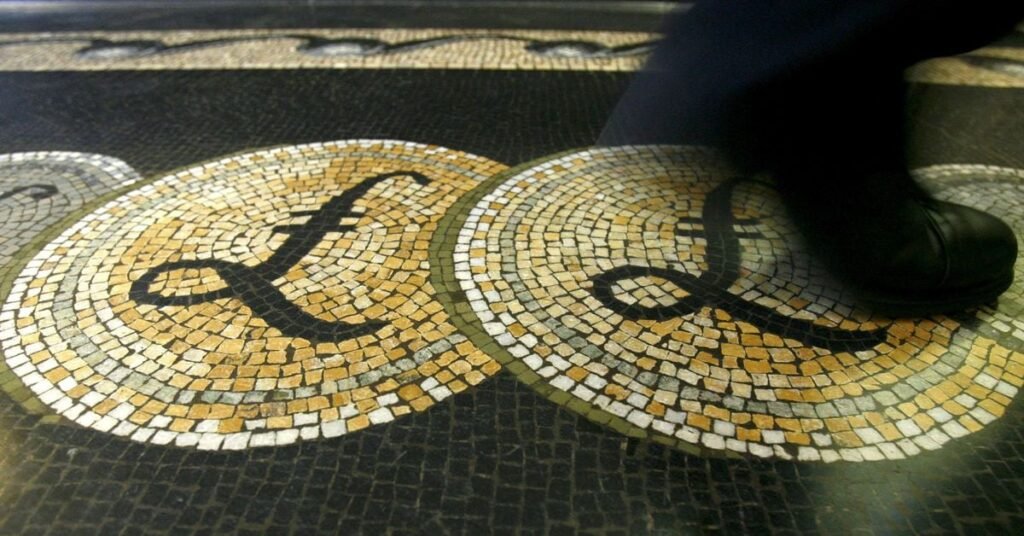 File photograph shows an employee walking over a mosaic depicting pound sterling symbols on the floor of the front hall of the Bank of England in London