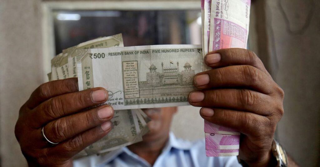 A cashier checks Indian rupee notes inside a room at a fuel station in Ahmedabad