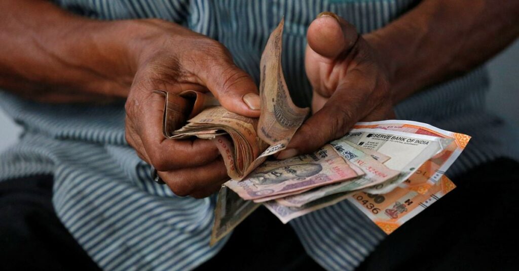 An attendant at a fuel station arranges Indian rupee notes in Kolkata