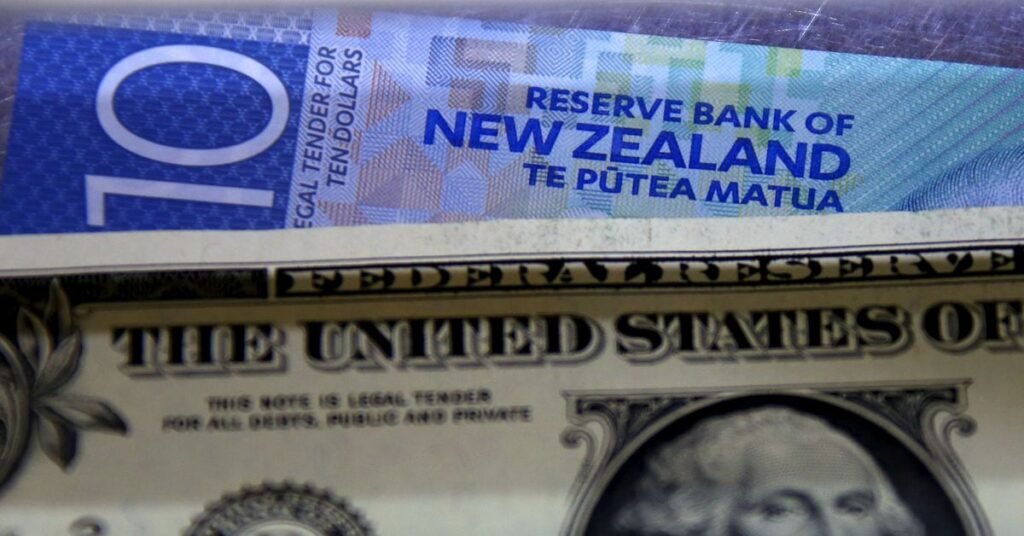 A New Zealand ten dollar note sits underneath a United States one dollar bill in the window of a currency exchange teller in Sydney, Australia