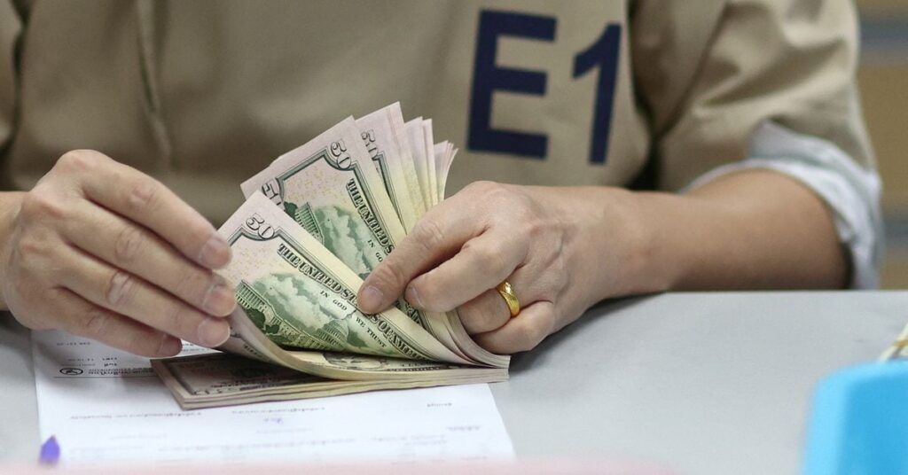 A bank employee counts U.S. dollar notes at a Kasikornbank in Bangkok