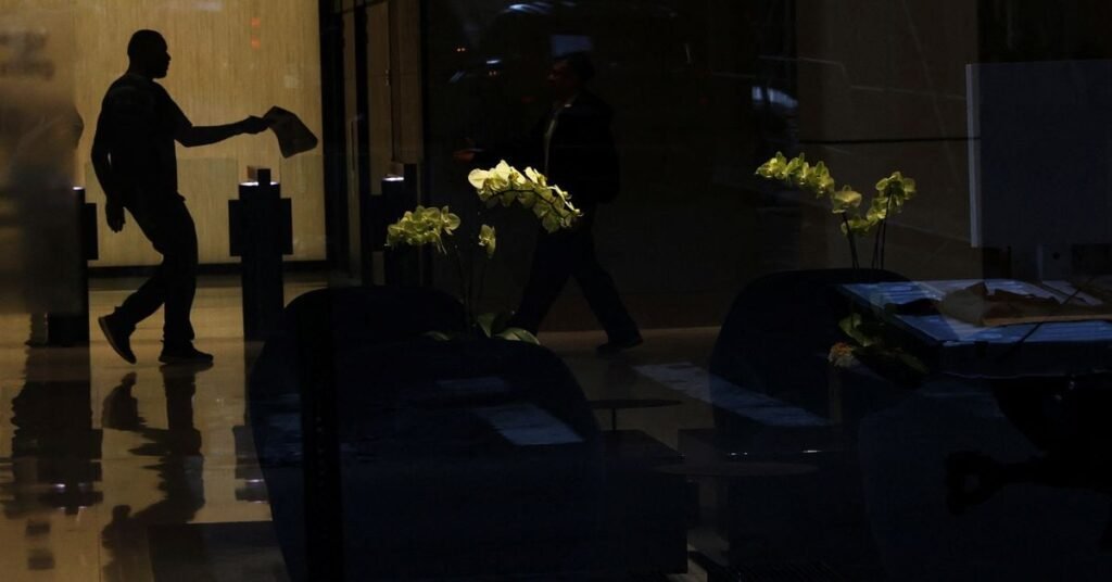 A man is seen in silhouette near flowers at an office building in the financial district of New York City,